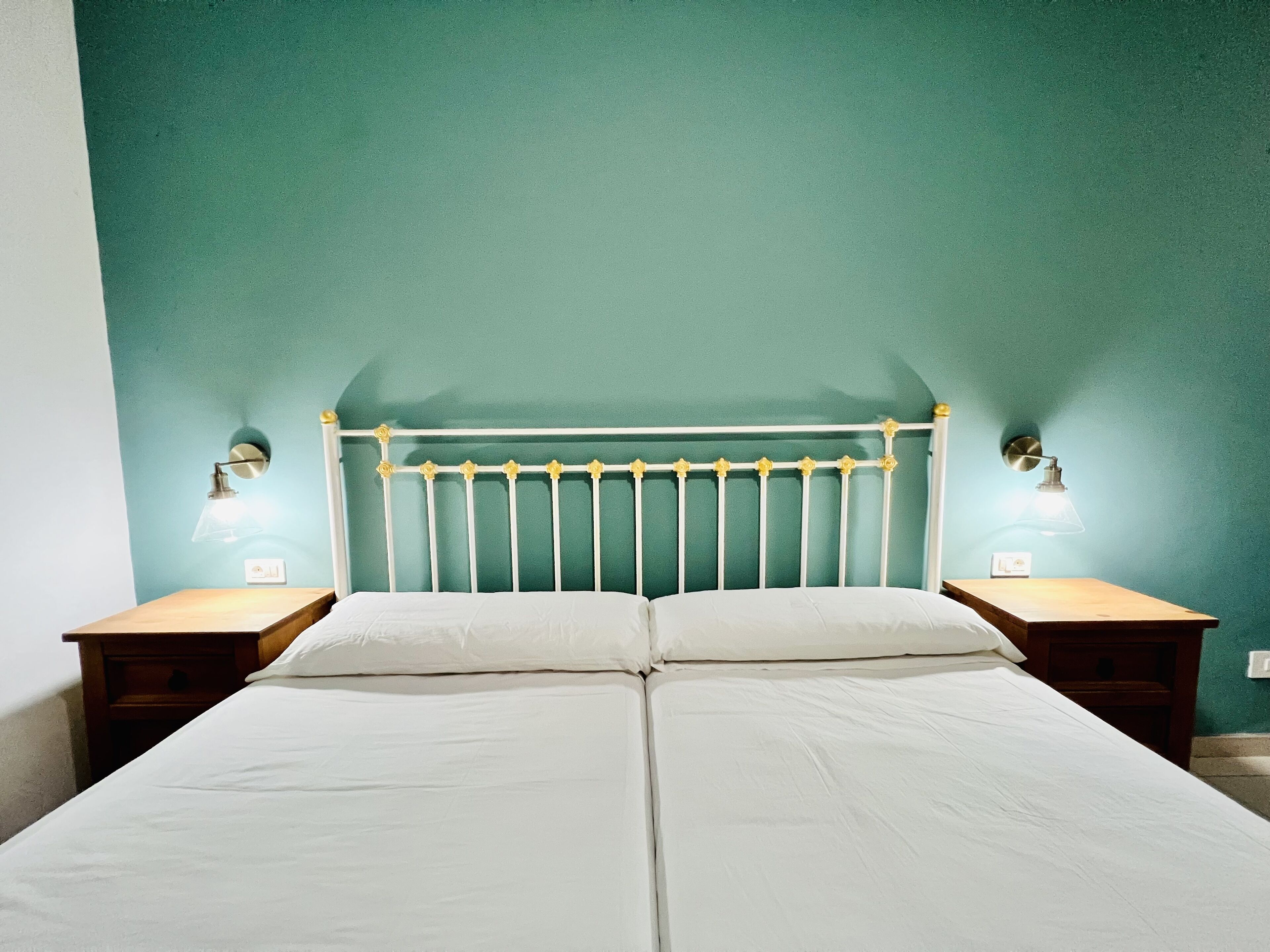 A double bed with a white headboard and two bedside lamps.
