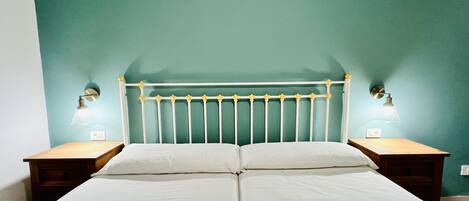 A double bed with a white headboard and two bedside lamps.