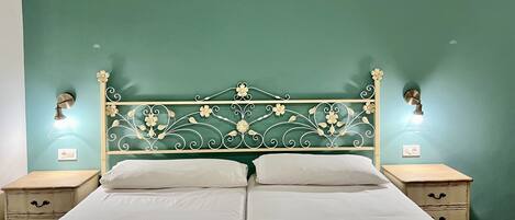 Un lit double avec une tête de lit décorative, deux tables de chevet et des lampes fixées au mur.