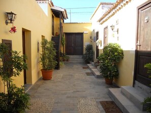 A narrow alleyway with potted plants and doors leading to buildings. - Casa Rural Anton Piche (Granadilla de Abona)