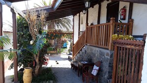 A covered outdoor area with a stone floor, wooden furniture, and a staircase leading to an upper level. - Casa Rural Anton Piche (Granadilla de Abona)