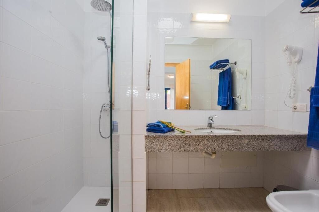 Un baño con cabina de ducha de vidrio, un lavabo con espejo y un teléfono.