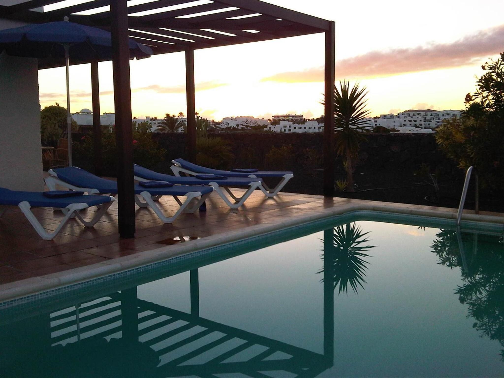 A pool area with lounge chairs and a pergola.