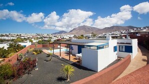 A rooftop terrace with a pool, white buildings, and a mountain in the background. - Villas Las Marinas (Yaiza)