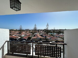 Un balcon donnant sur un quartier résidentiel, avec des maisons et un ciel dégagé.