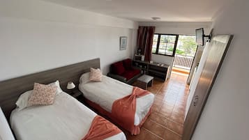 Habitación de hotel con dos camas, un sofá, una mesita y un televisor.