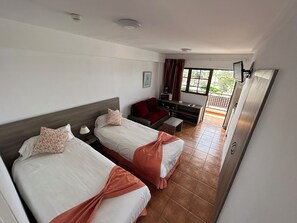 Habitación de hotel con dos camas, un sofá, una mesita y un televisor.