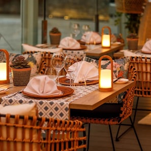 A dining area with tables set for two, featuring woven chairs, placemats, and candle-lit centerpieces. - Santa Mónica Suites Hotel (San Bartolome de Tirajana)