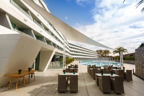A modern hotel with a pool area, outdoor seating, and a unique architectural design. - Santa Mónica Suites Hotel (San Bartolome de Tirajana)