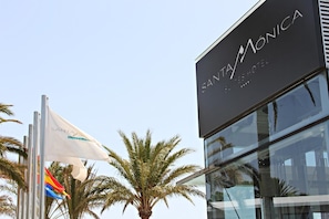 A hotel sign with 'SANTA MONICA' and 'SANTA MONICA HOTEL' text, a palm tree, and a modern building facade.