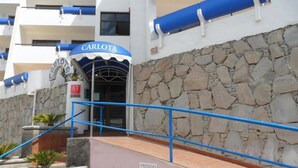 Entrada de un hotel con pared de piedra y barandilla azul.