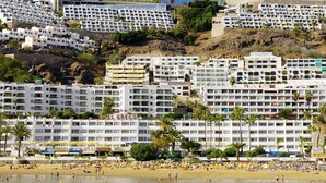 A coastal hotel with multiple floors, beachside location, and visible signage for amenities. - El Greco (Mogan)