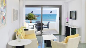 A hotel room with a balcony, a sofa, a coffee table, a TV, and artwork on the walls. - El Greco (Mogan)