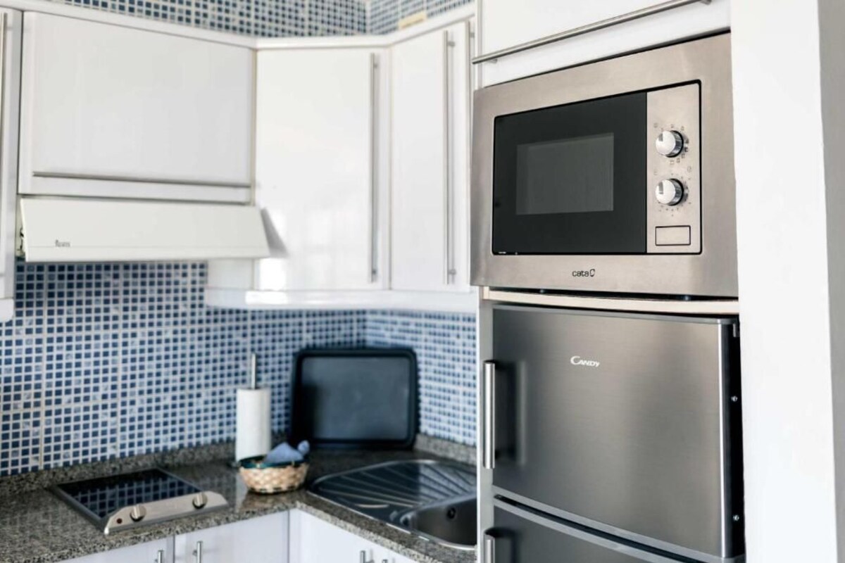 A kitchen with white cabinets, a microwave, and a built-in oven.