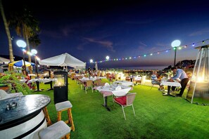 An outdoor dining area with tables and chairs, string lights, and a tent. - Apartamentos Rio Piedras (Mogan)