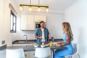 Una cocina moderna con armarios blancos, un lavamanos de acero inoxidable y un microondas empotrado.