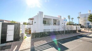 A modern building with a white facade, a gated entrance, and a paved sidewalk. - Apartamentos Miami Playa (San Agustän)