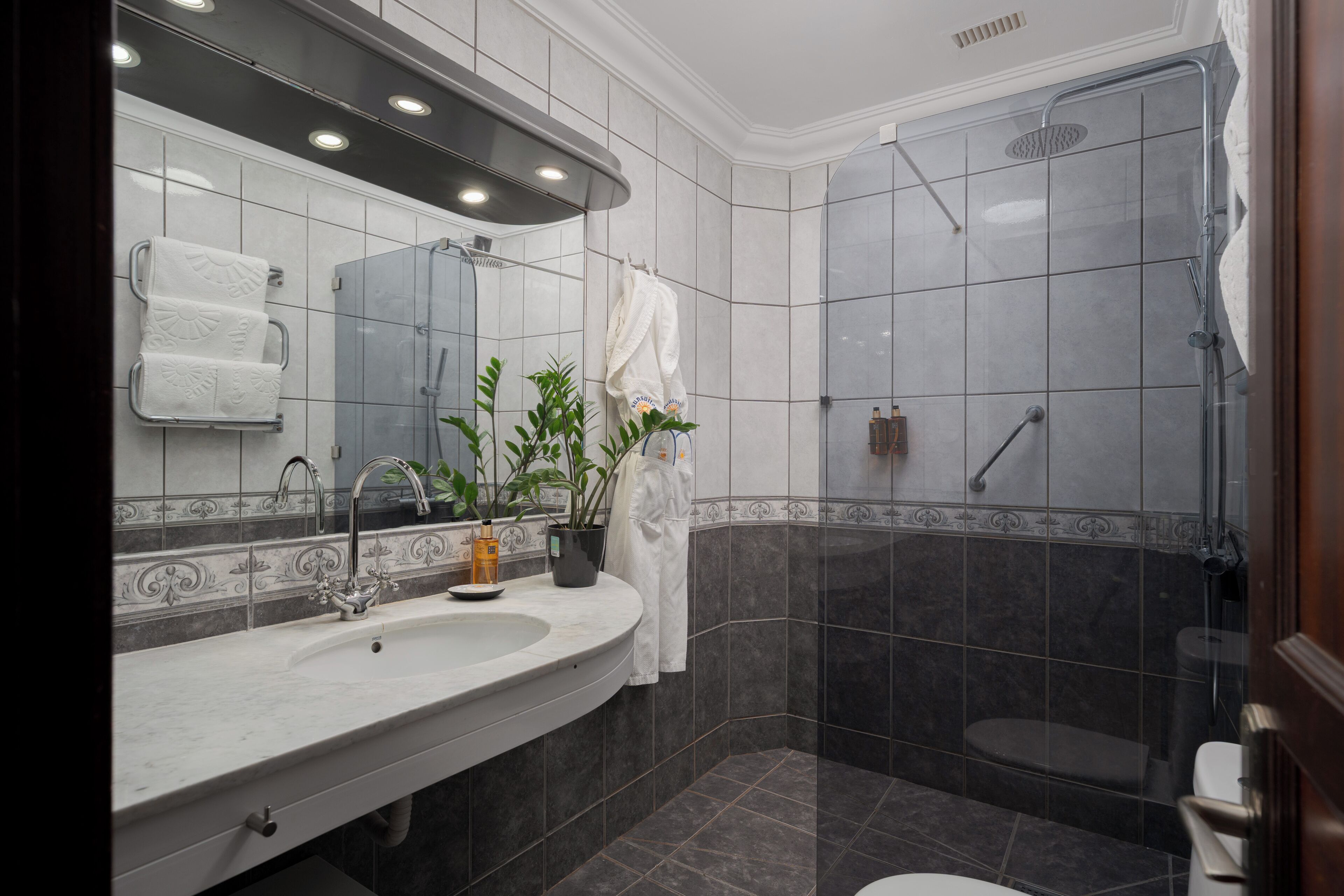 A bathroom with a sink, mirror, towel rack, shower, and toilet.