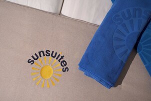 A towel with 'sunsuites' and a sun design on a beige surface.