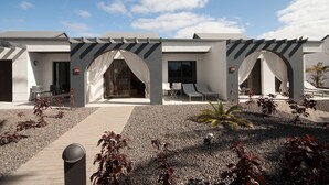 Un hôtel moderne doté d’un espace extérieur aménagé et couvert, d’un chemin de gravier et d’un petit jardin avec des plantes.