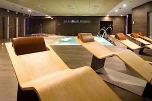 A modern spa area with wooden loungers, a central hot tub, and a sign reading "Las Lomas de Tarajal". - R2 Romantic Fantasia Dreams & Suites Hotel – Adults Only - All inclusive (Tuineje)