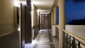 A corridor with a tiled floor, a wooden door at the end, and a railing on the right. - Hotel Playa Calera (Valle Gran Rey)