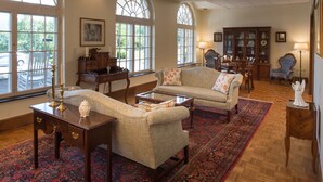 A spacious living room with a large window, a fireplace, and a dining area. - Lambuth Inn at Lake Junaluska (Lake Junaluska)