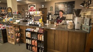 A coffee shop counter with a variety of coffee beans, a coffee machine, and a menu board. - Lambuth Inn at Lake Junaluska (Lake Junaluska)