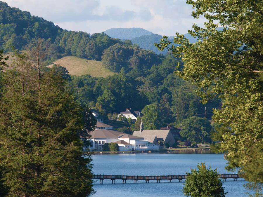 A lakeside view with a bridge, houses, and a golf course.