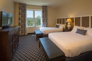 Two single beds with white linens and dark headboards, a television and lamp, and a window with a view.
