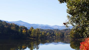 A calm lake reflecting trees and mountains.
