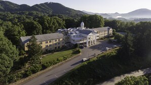 A large, multi-story building with a central dome, surrounded by lush greenery and hills. - Lambuth Inn at Lake Junaluska (Lake Junaluska)
