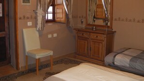A bedroom with a bed, a chair, a wooden dresser, and a mirror. - Hotel Casa El Zaguan (Vilaflor)