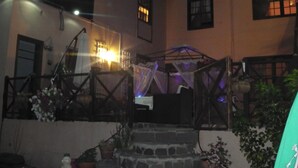 A courtyard with a stone staircase leading to a wooden gate, surrounded by potted plants and a small table with a chair. - Hotel Casa El Zaguan (Vilaflor)