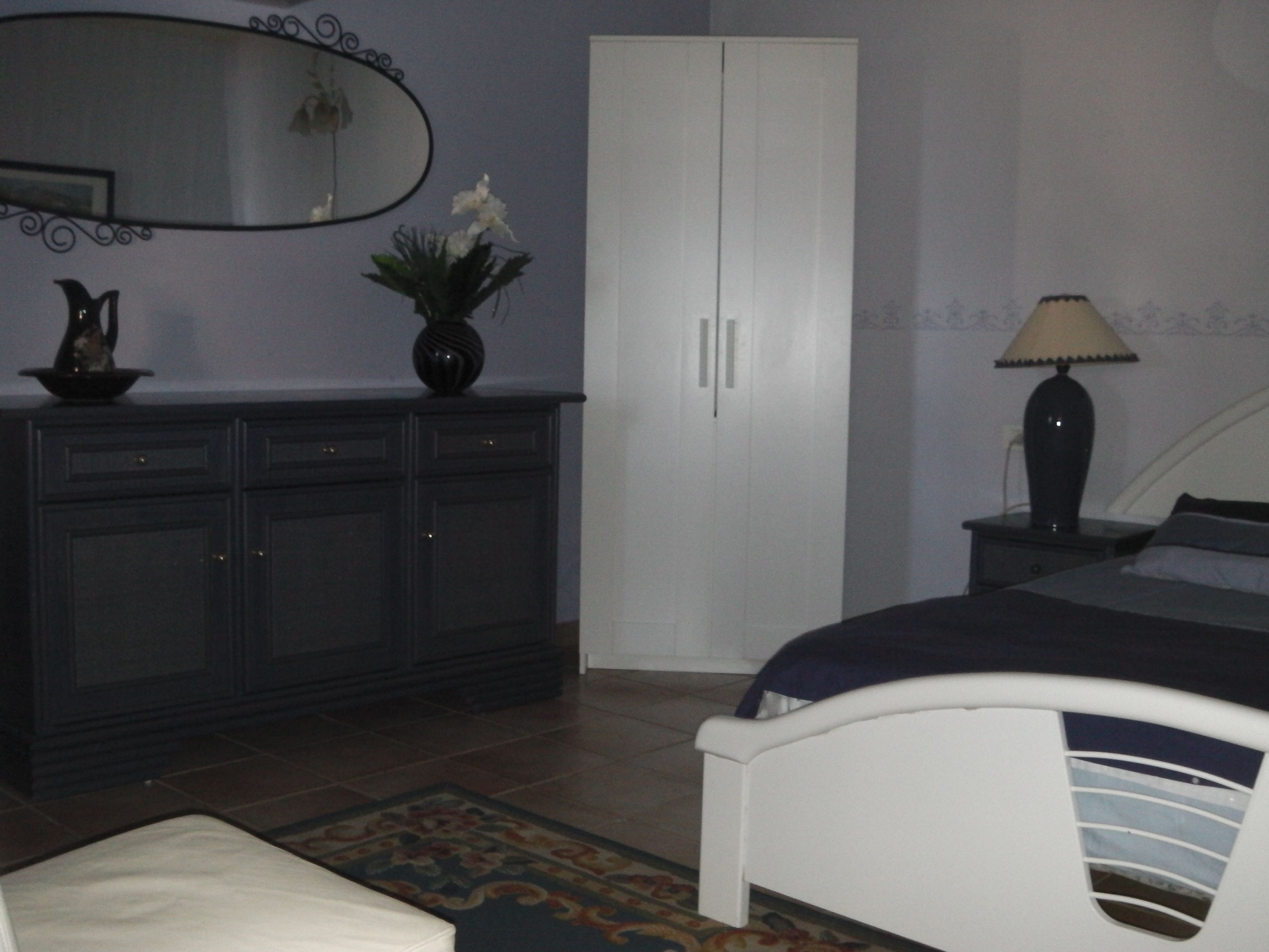 A bedroom with a bed, a dresser, a mirror, and a nightstand.