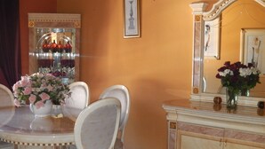 A dining area with a round table, white chairs, a vase of flowers, a mirror, and a decorative cabinet. - Hotel Casa El Zaguan (Vilaflor)