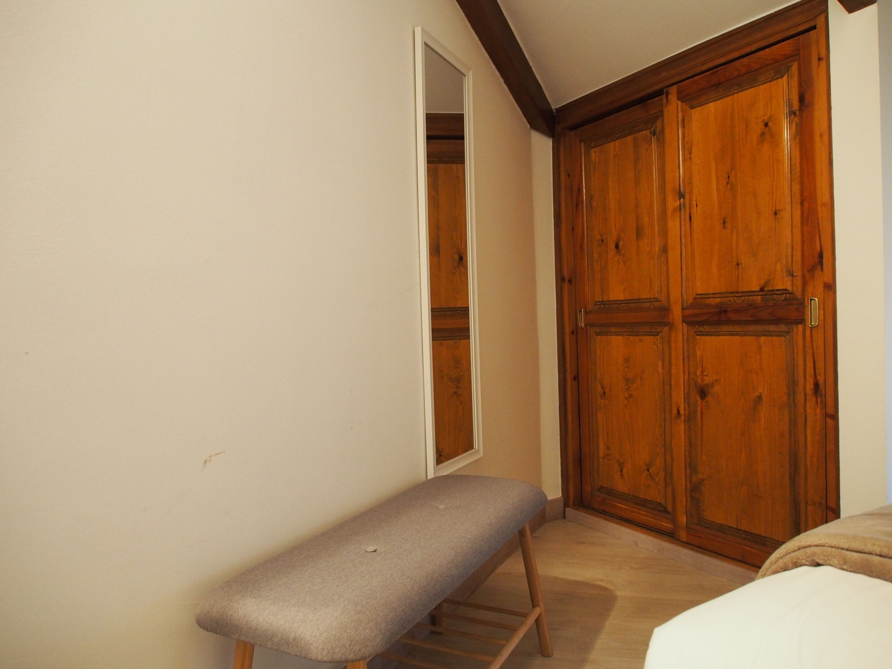 Une pièce comprenant un banc, une armoire en bois et un miroir.