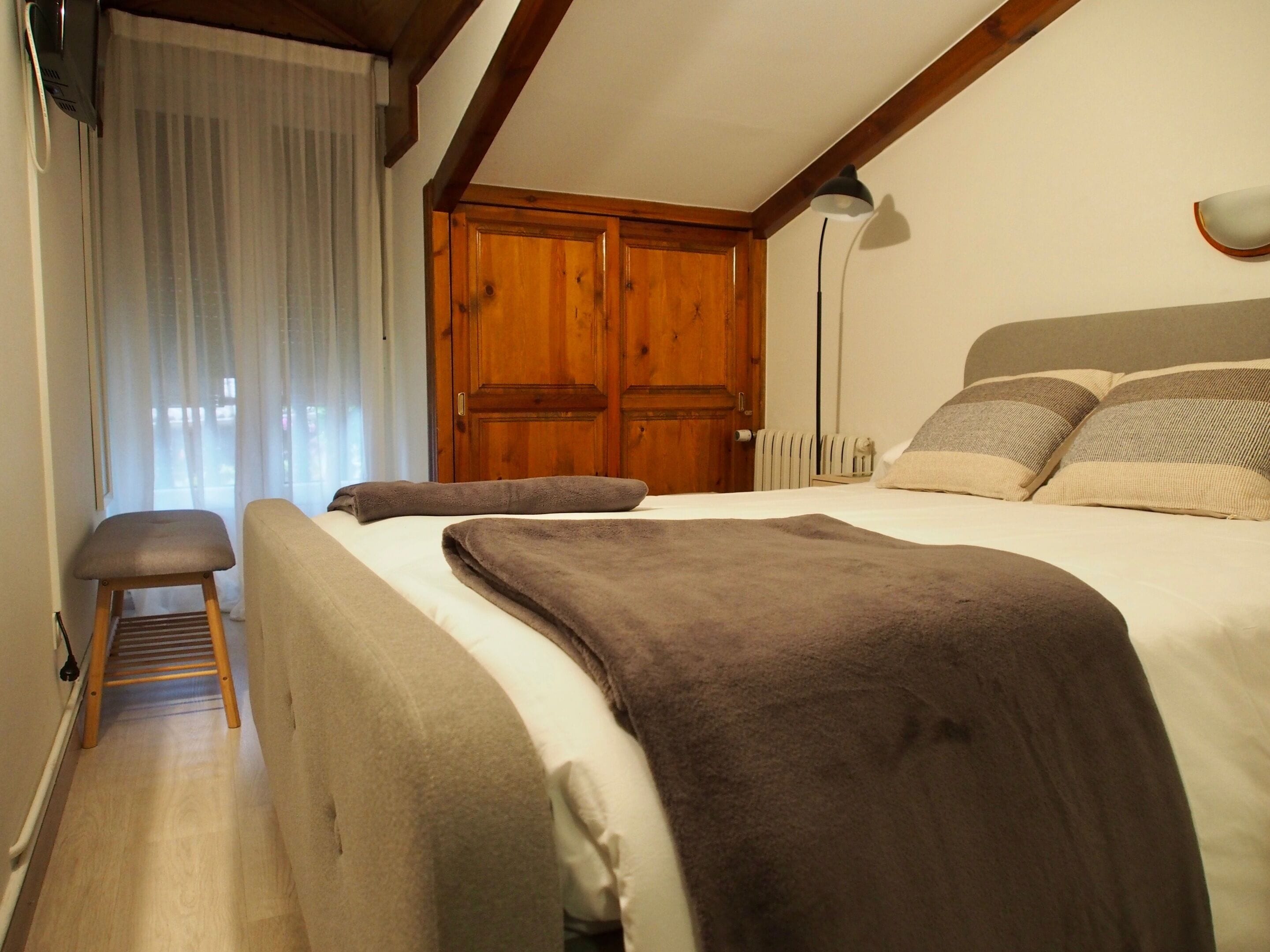 Un dormitorio con un armario de madera, una lámpara de noche y una silla.