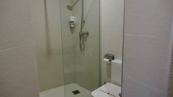 Un baño pequeño y moderno con ducha envuelta en vidrio, inodoro y secador de manos.