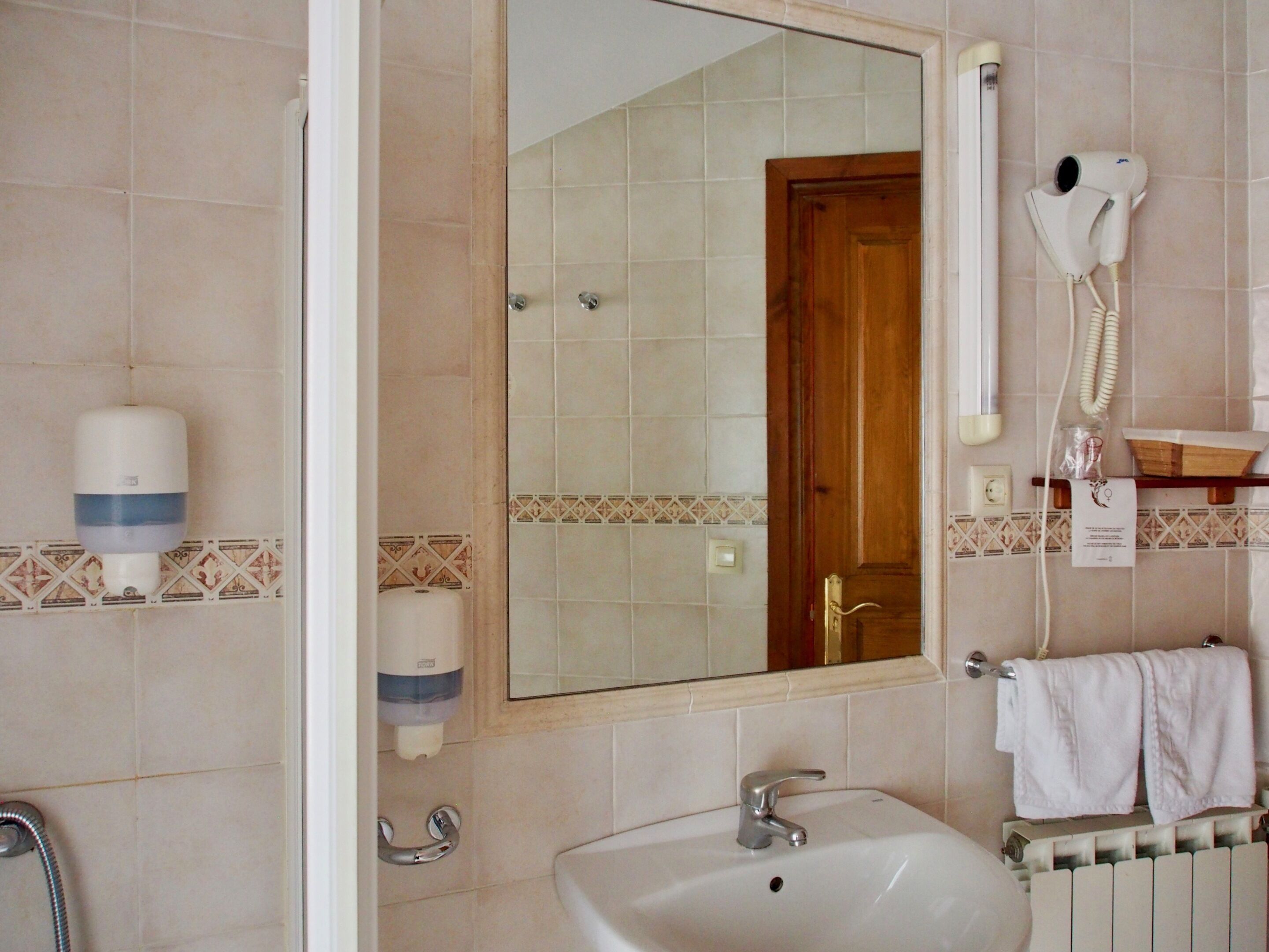 Baño con lavamanos, espejo, secador de pelo y toallero.