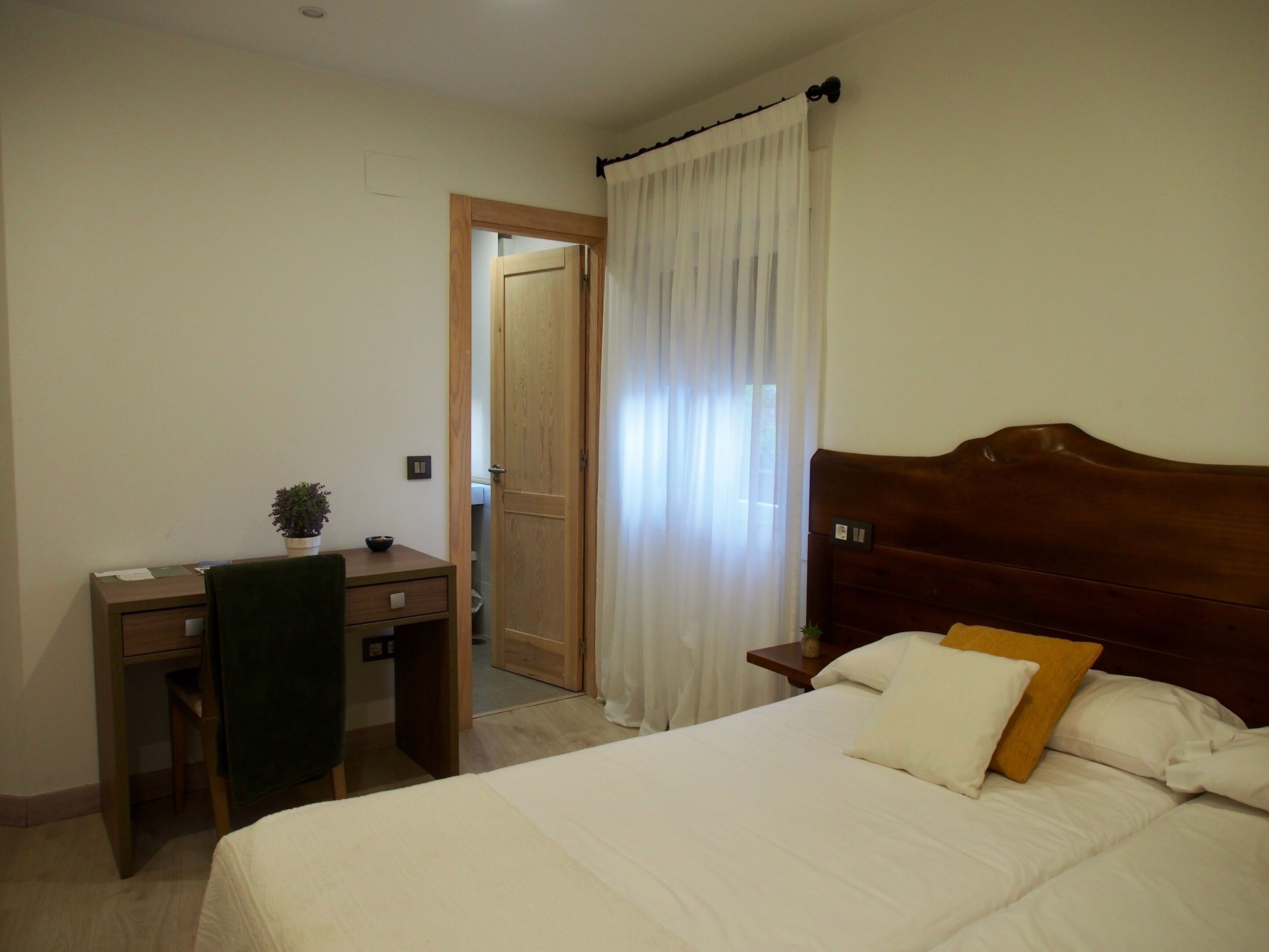 Un dormitorio con cama, escritorio, silla y mesita de noche.