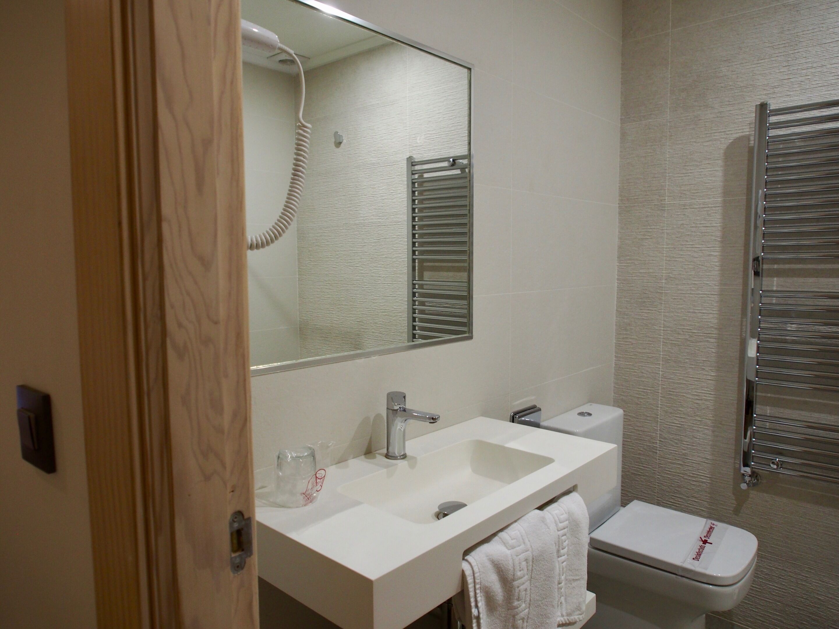 A bathroom with a white sink, mirror, and toilet.