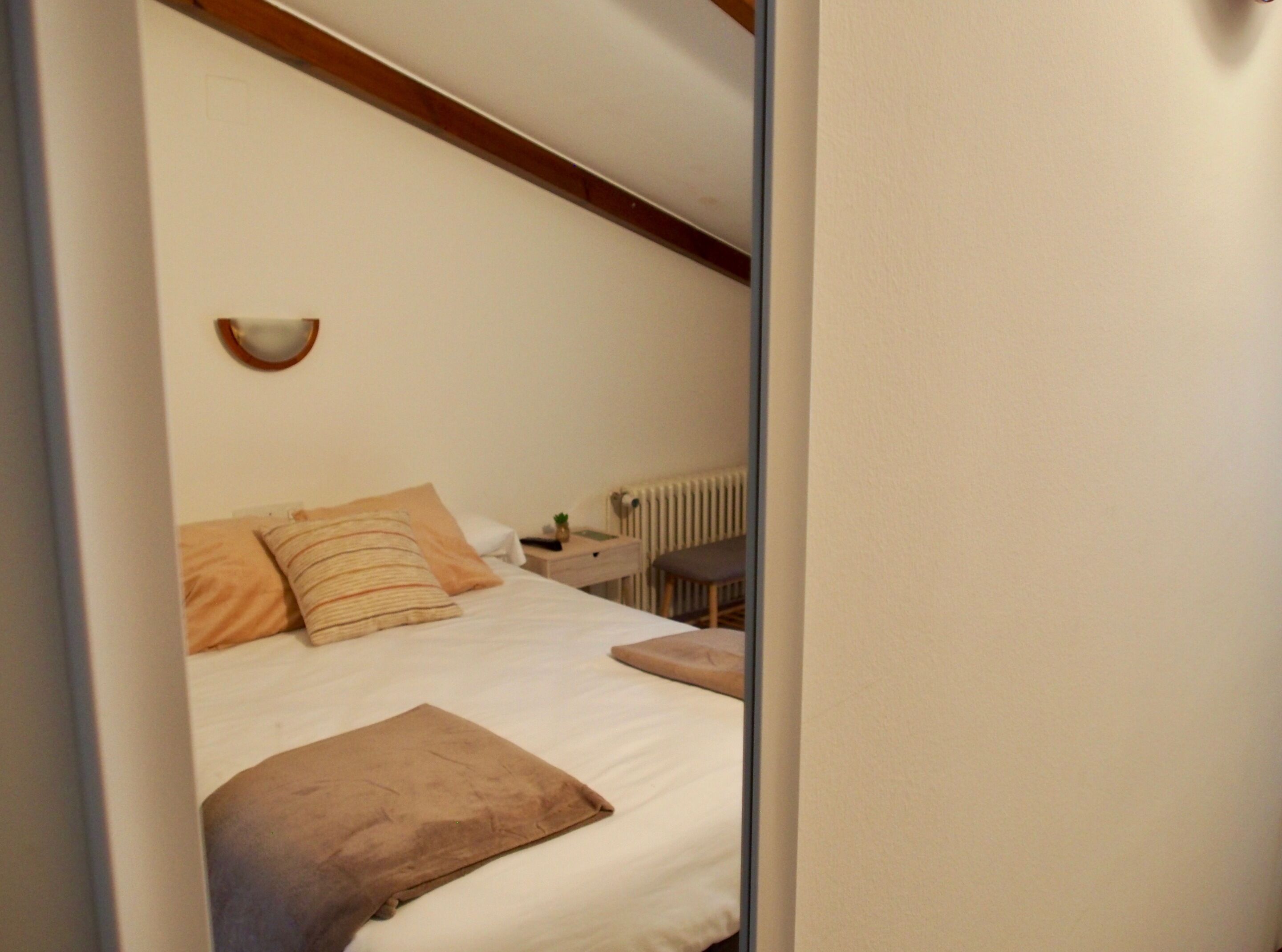 A bedroom with a bed, a bedside table, a lamp, and a radiator.