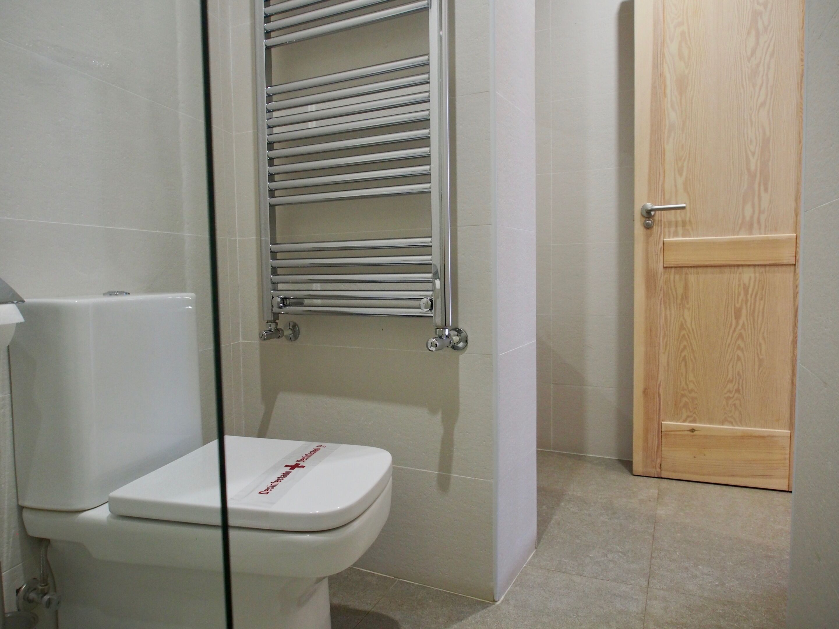 Un baño con inodoro blanco, cabina de ducha de cristal y puerta de madera.
