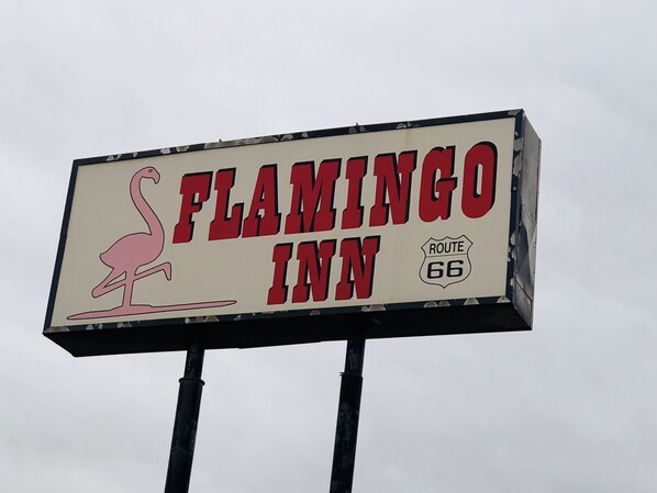 A sign for Flamingo Inn with a flamingo graphic and Route 66 symbol.