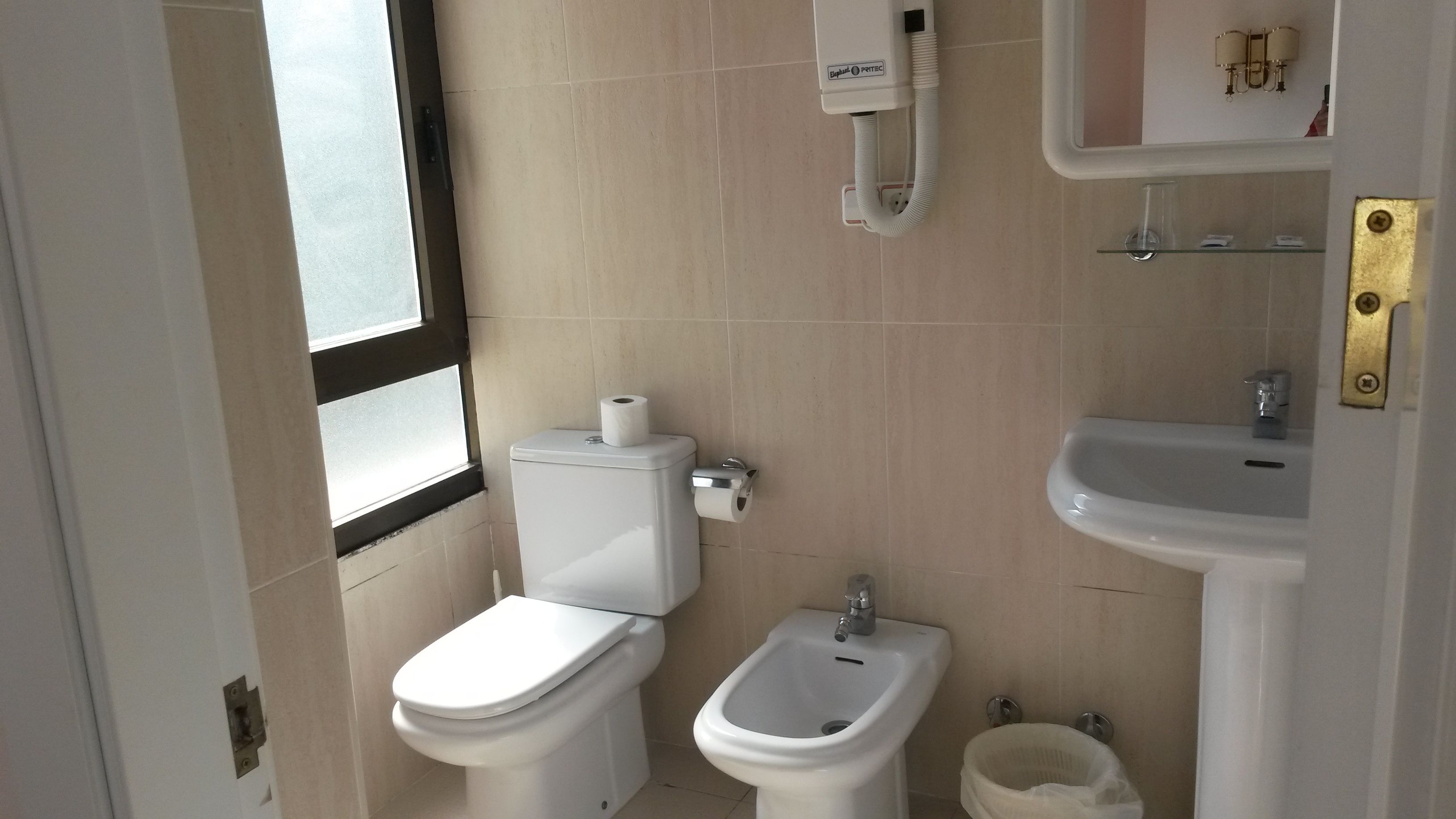 A small bathroom with a toilet, bidet, and sink.