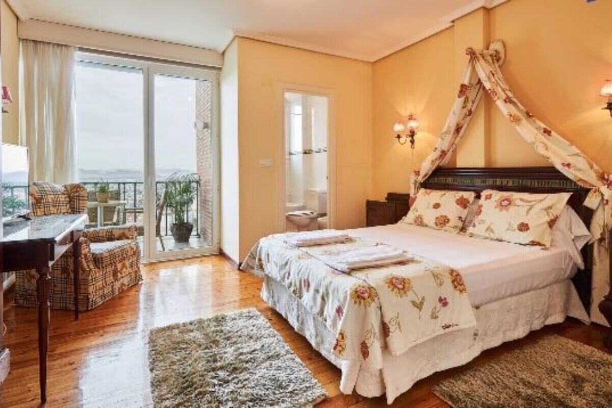 Ein Schlafzimmer mit Bett, einem Balkon mit Tisch und Stühlen sowie Blick auf die Stadt.