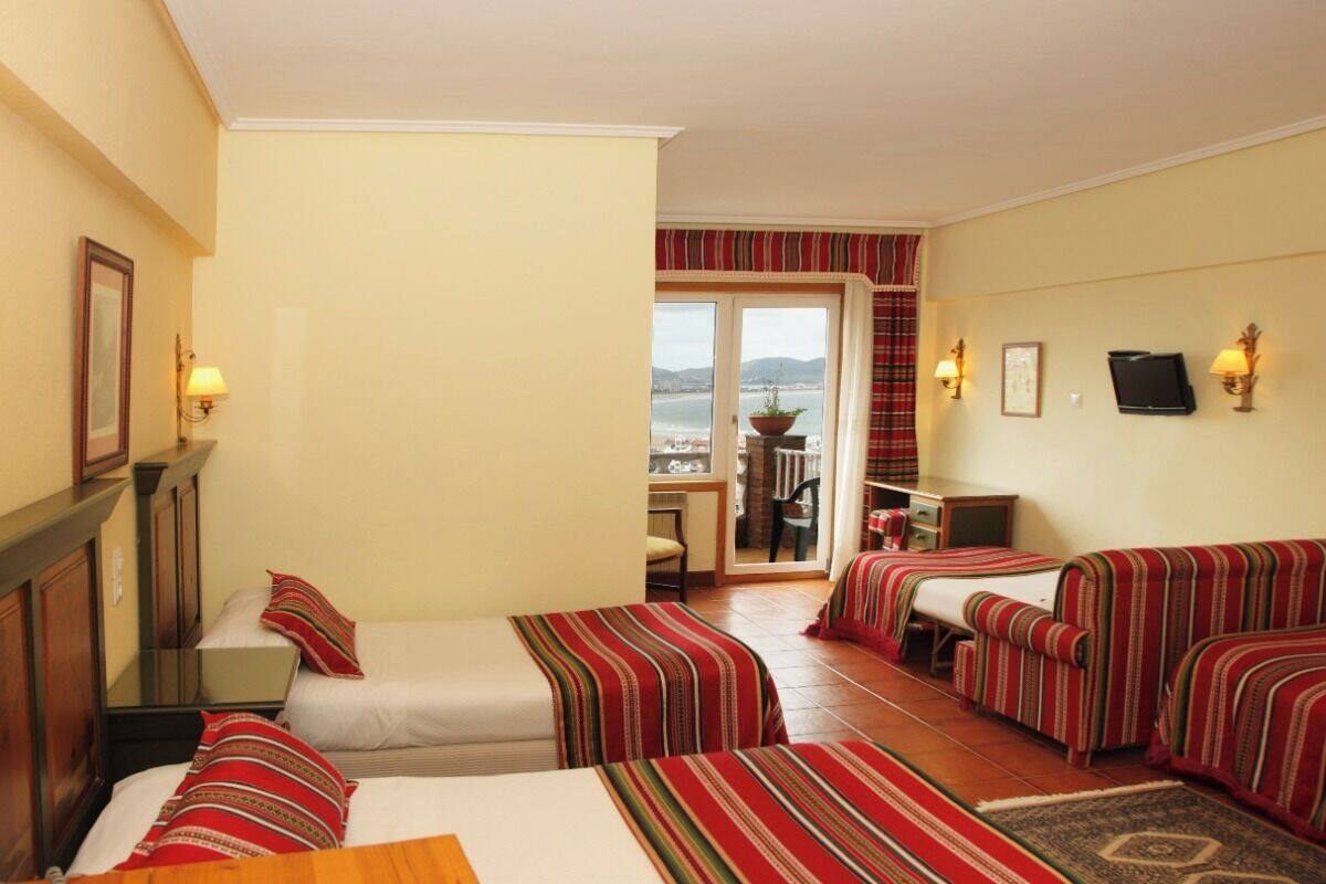 Ein Hotelzimmer mit zwei Betten, einem Schreibtisch und Meerblick.