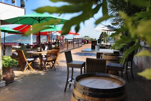 An outdoor patio with wicker furniture, wooden tables, and green umbrellas.