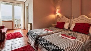 A bedroom with a large bed, a nightstand, a red rug, and a window with a view. - Hotel Risco (Laredo)